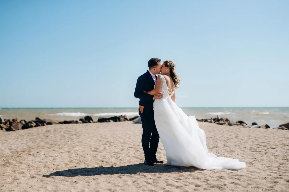 Bride and groom kissing on a beach on a clear sunny day