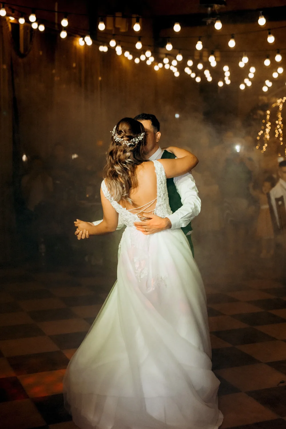 Bride and groom sharing their first dance under warm string lights